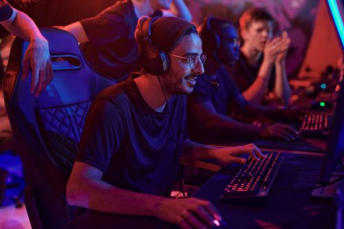 Online gaming players wearing headsets competing on PCs in a neon-lit esports setup